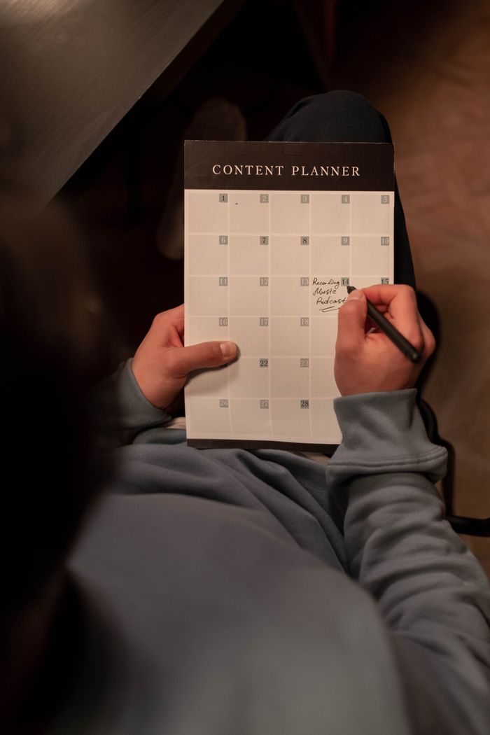 project-02-d Person planning content on a calendar in a cozy indoor setting.